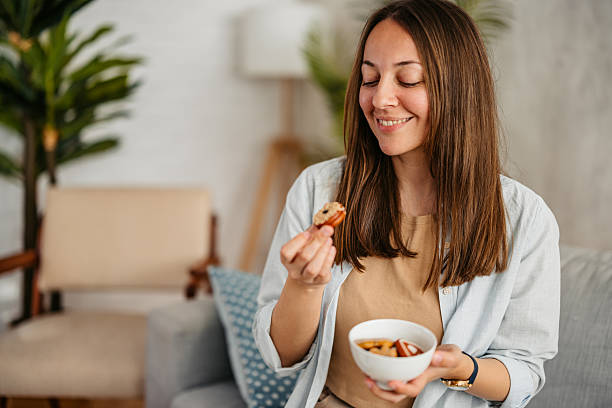 istock Young Woman Eating Cookies While Sitting On The Sofa 2219329327