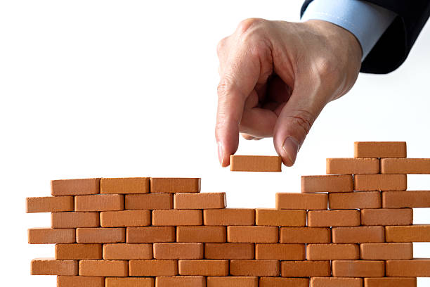 istock Businessman putting toy brick onto a wall 2219335099