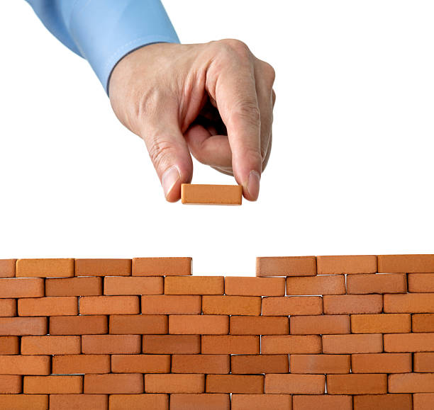 istock Businessman putting toy brick onto a wall 2219335101