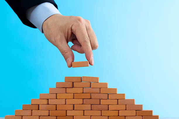 istock Businessman putting toy brick onto a pyramid 2219335106