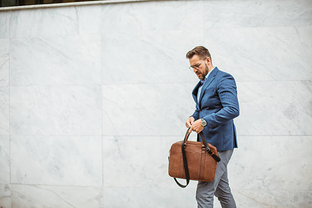 istock Businessman adjusting his leather bag while walking in the city 2219335340