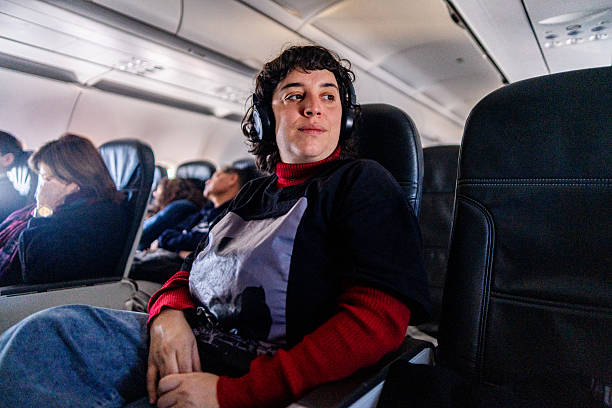 istock Mid adult woman using wireless headphone on a plane 2219335358