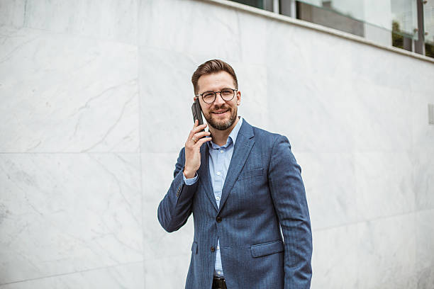 istock Businessman talking on smartphone in front of marble wall 2219335472