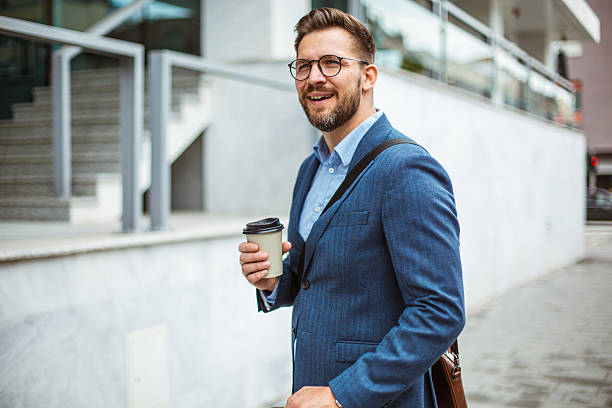 istock Businessman walking and holding coffee outside office building 2219336590