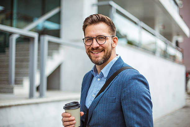 istock Smiling businessman holding coffee outside office building 2219336621