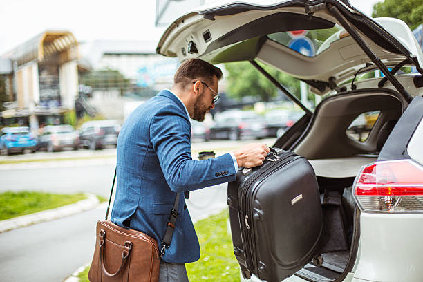 istock Businessman loading luggage into car trunk before business trip 2219336911