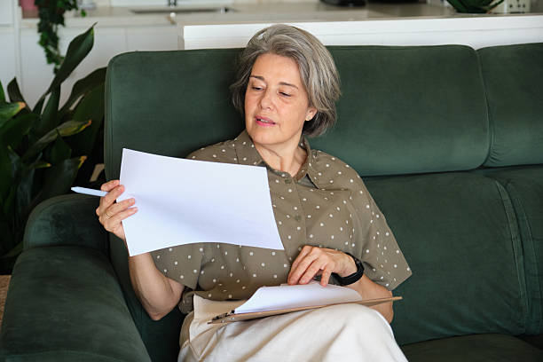 istock Senior woman reviewing documents while sitting comfortably on a sofa 2219337697