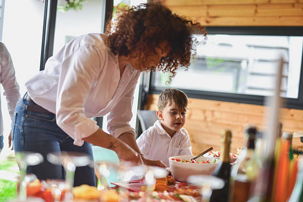 istock Cute Boy Looking at Buffet With Curiosity While His Mother is Slicing Orange 2219337802