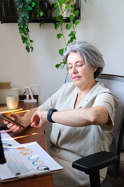 istock Businesswoman checking time on smartwatch while working at home office desk 2219340009