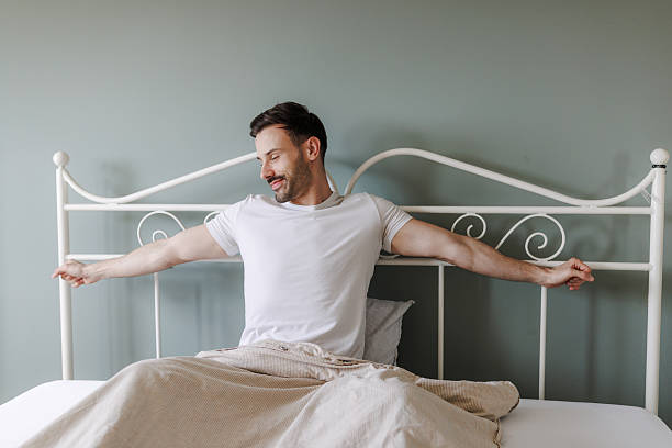 istock Man stretching and smiling while sitting in a cozy bedroom 2219340706