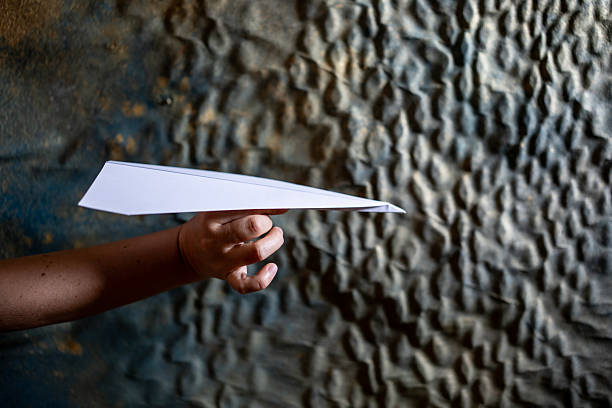 Boy Holding Paper Airplane While Standing Against Sky