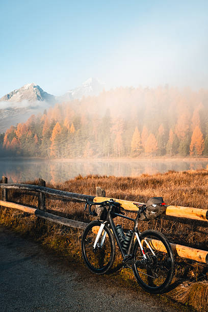 Bike parked against fence on roadside in autumn, lake and mountains distant, bike packing around Engadine Alps, Graubunden Canton, Swiss Alps