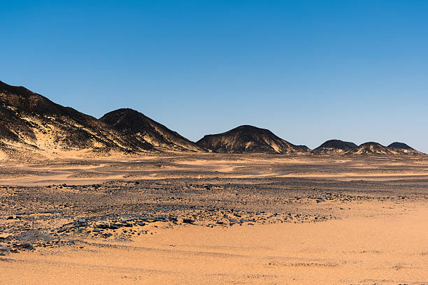 Ash-covered hills in Egypt's Black Desert under a clear sky, scenic and remote landscape. Volcanic mountains
