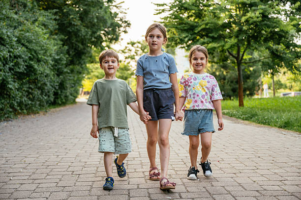 istock Three elementary age sisters and brother playing in the park on sunny day 2219358520