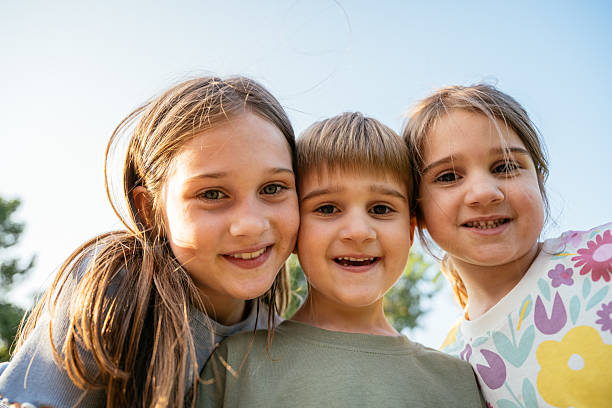 istock Three cool siblings playing in the park on sunny day and looking down at the lens 2219358589
