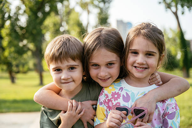 Directly below shot of happy children embracing each other having fun and smiling at camera with a sky background, a group of joyful kids playing together outside. . High quality photo