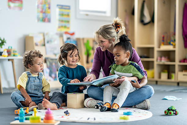 istock Teacher Reading Book to Young Children in a Playroom Setting 2219363276