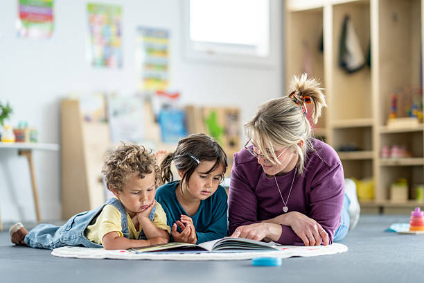 istock Teacher Reading Book with Children in a Bright Classroom Setting 2219363560