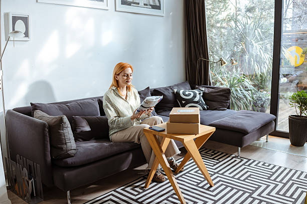 istock Woman opening parcel packaging in bright living room 2219365347