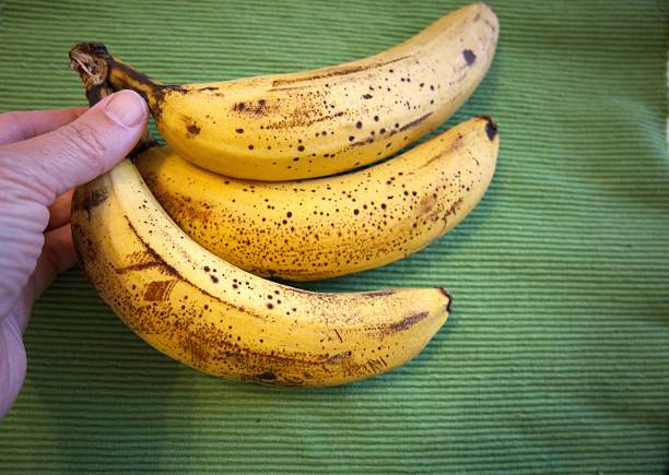 istock Yellow and brown banana with green background 2219369721