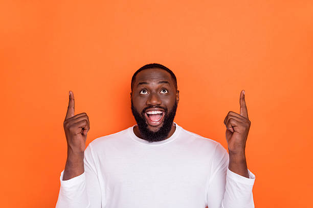 istock Photo of funny excited guy dressed white pullover pointing up empty space isolated orange color background 2219370689