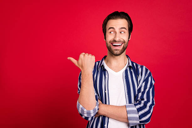 istock Photo of young cheerful guy curious look indicate finger empty space ads recommend isolated over red color background 2219370955