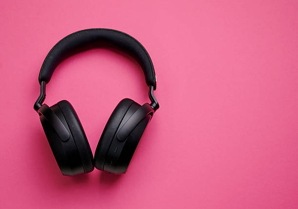istock Black wireless headphones resting on a vibrant pink surface during daylight hours 2219371253