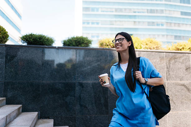 istock Young nurse walking with coffee and backpack near hospital 2219371278