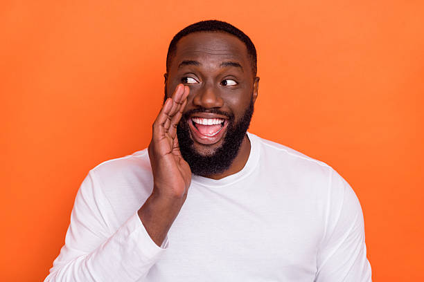 istock Photo of tricky cunning guy dressed white pullover telling secret empty space isolated orange color background 2219373360