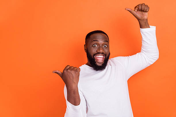 istock Portrait of attractive cheerful guy pointing forefingers copy blank space ad solution isolated over bright orange color background 2219373715