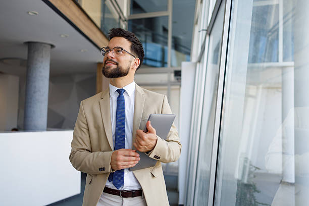 istock Professional businessman navigating sleek corporate interior, examining tablet with strategic focus, contemplating business solutions 2219373996
