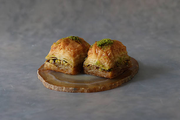 istock Traditional turkish baklava with nuts and honey on a plate isolated on a concrete pattern background. 2219374020