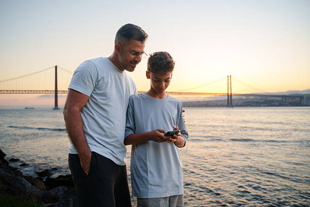 istock Father and son using cell phone outdoors 2219376193