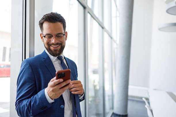 istock Young businessman using a smartphone in a sleek modern office, engaging in seamless communication and networking while smiling confidently 2219379660