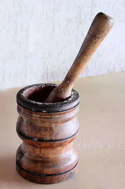 A wooden pestle with garlic and salt pounded on the table