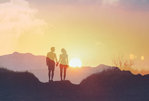 istock Couple holding hands and walking in natural sunset setting. 2219389649