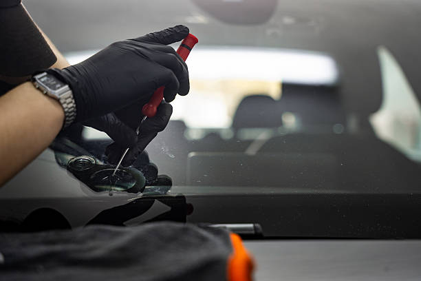 istock Technician uses a metal tool to apply controlled pressure on a glass chip. Awl is placed at the edge of a windshield crack for inspection or chip preparation. 2219389681