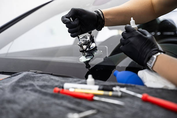 Resin repair on windshield using injector application to restore structural clarity. Windshield crack repair using resin injection. Technician using windshield injector tool to fix bullseye crack