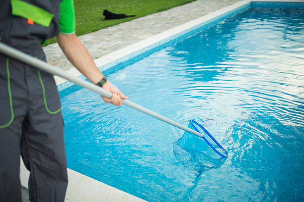istock Close-up of a worker using a netting tool for swimming pool cleaning. 2219391407