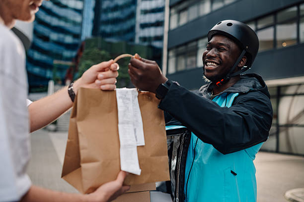 istock Smiling delivery man delivering food order to a customer 2219394067