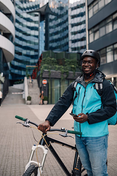istock Smiling bicycle courier holding smartphone and looking away 2219394357