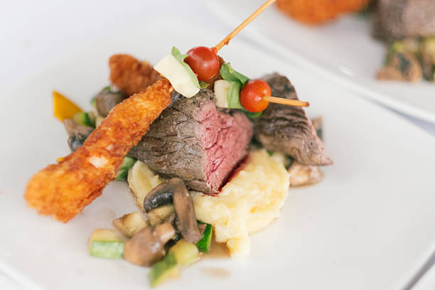 Close-up of a gourmet dish featuring grilled beef tenderloin, fried shrimp, mashed potatoes and sauteed vegetables