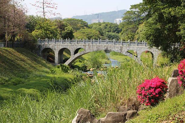 A bridge over a river with a flower on the right side. The bridge is made of stone