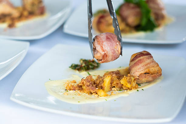 istock Chef using tongs to place chicken wrapped in bacon on plate 2219396849