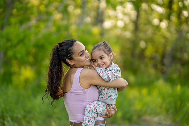 Mother hugging her two-year-old daughter in a studio shot on white background with copy space
