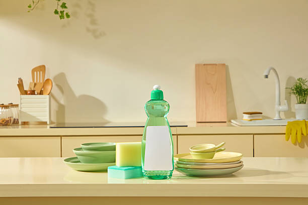 istock A green detergent bottle stands on a bright counter, surrounded by neatly stacked plates, creating a warm, everyday kitchen lifestyle setting. Scene for advertising, space for design label 2219403806