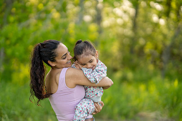 istock Mother Hugging Her Daughter in a Sunny Green Nature Setting 2219407062