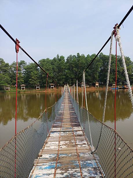 istock Rustic Wooden Suspension Bridge Over Calm Waters 2219410697