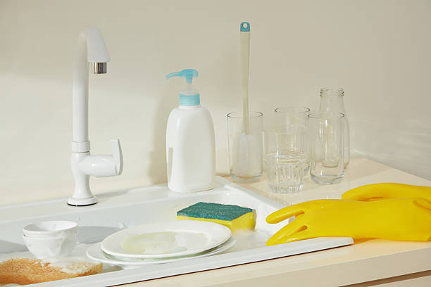 Assorted cleaning products like pump bottles, sponges, and gloves neatly displayed on a kitchen counter, set for a deep cleaning day.