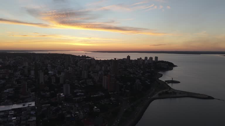 Aerial view of city buildings silhouetted against a dramatic sunset over the Paraná River, Posadas, Misiones, Argentina.